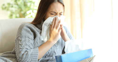 Woman blowing her nose in a tissue because she has a cold
