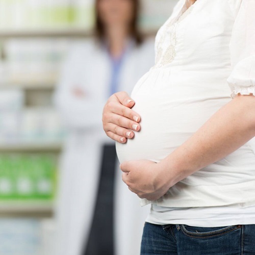 Woman holding her pregnant belly in front of a pharmacist