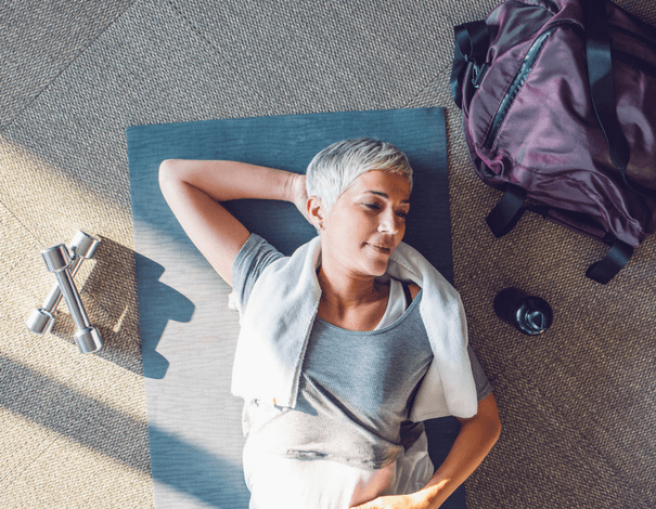 Elder woman lying down on the floor on a yoga mat