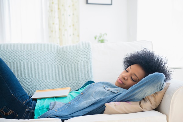 Woman napping on a couch with a book on her stomach