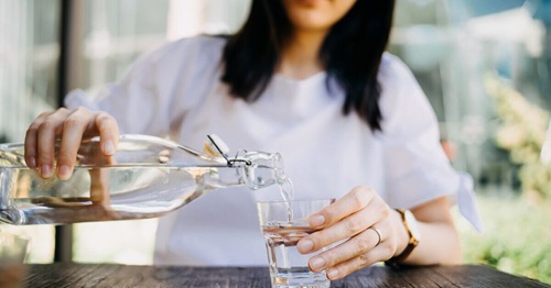 Femme se versant un verre d'eau afin de s'hydrater