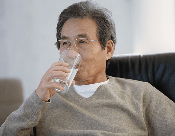 Homme adulte buvant un verre d'eau