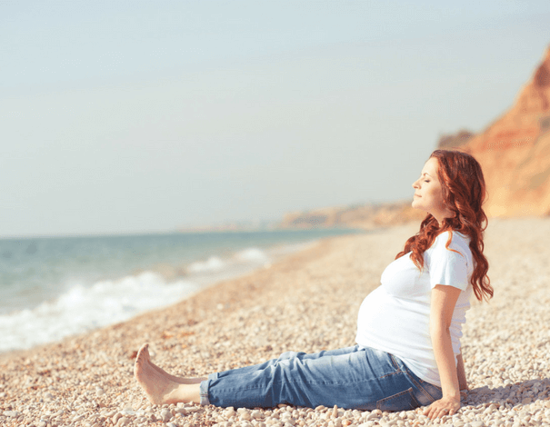 Femme enceinte assise sur la plage